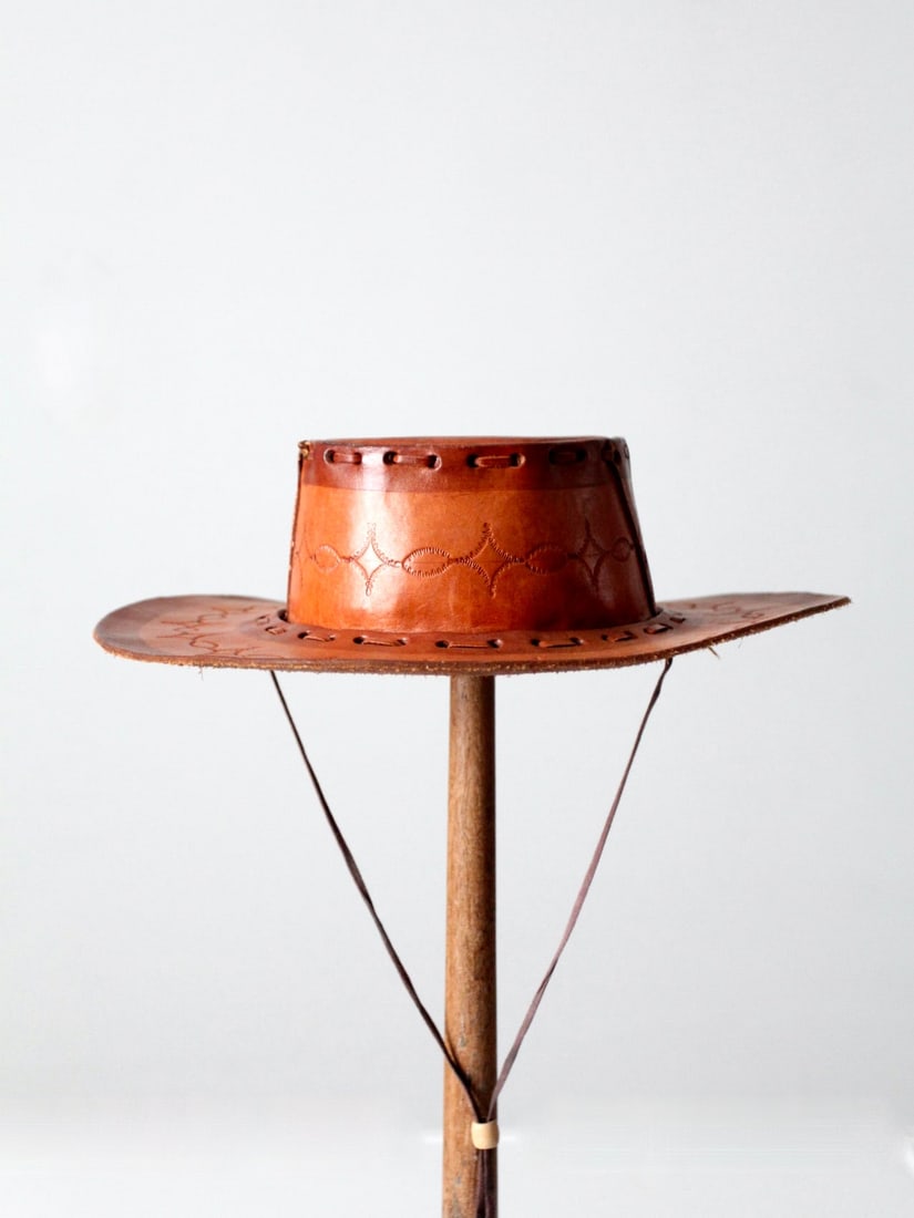 Vintage Mexican Tooled Leather Hat with Stiff Brim: Vintage Mexican Tooled Leather Hat with Stiff Brim Discover a unique piece of craftsmanship with this vintage Mexican tooled leather hat. Made from high-quality tan leather, this hat features a stiff