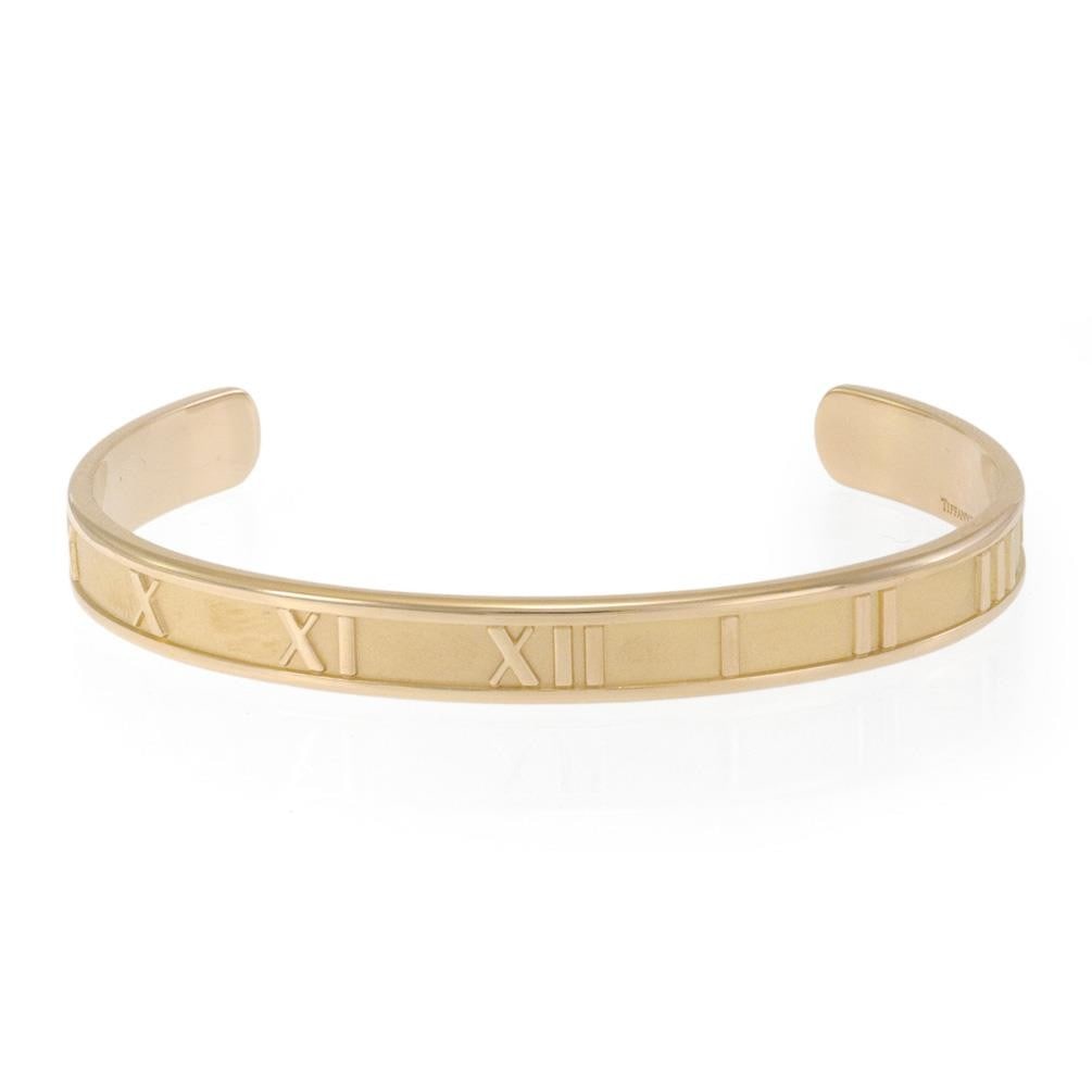 Tiffany & Co. 18k Yellow Gold Atlas Cuff Bracelet Roman Numerals: Tiffany & Co. 18k Yellow Gold Atlas Cuff Bracelet Roman Numerals This exquisite cuff bracelet from the ATLAS Collection by Tiffany & Co. features a bold design crafted from 18k yellow gold with a poli