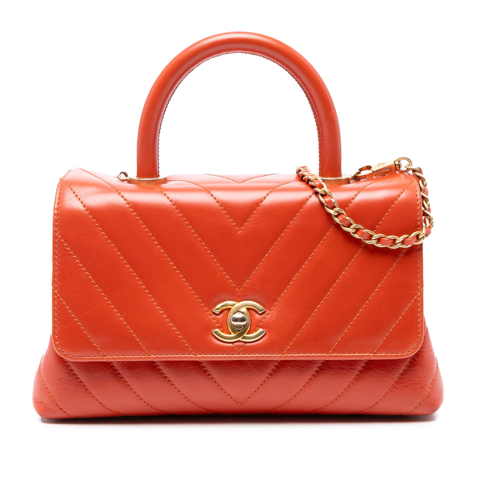 Chanel Mini Chevron Lambskin Top Handle Bag in Orange: Chanel Mini Chevron Lambskin Top Handle Bag in Orange Elevate your accessory collection with the Chanel Mini Chevron Lambskin Coco Top Handle Bag. This exquisite bag showcases a quilted chevron design