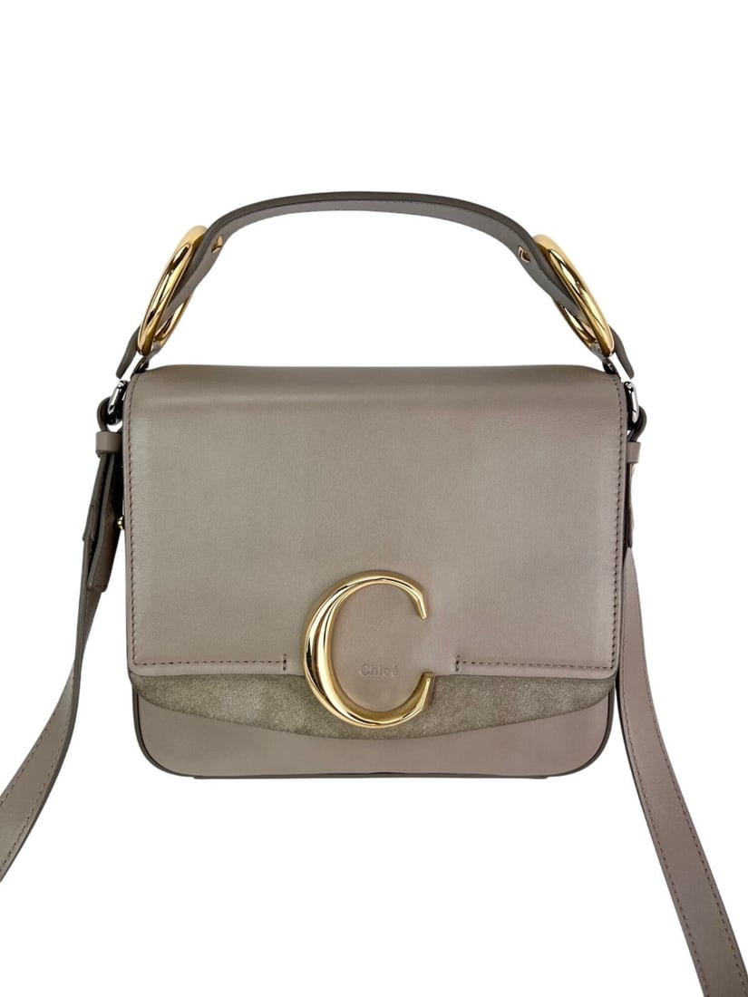 Chloe C Motty Gray Suede Shoulder Bag with Gold Silver Hardware: Chloe C Motty Gray Suede Shoulder Bag with Gold Silver Hardware Elevate your accessory collection with the Chloe Shiny Calfskin Suede Small C Motty Gray Shoulder Bag. This stylish trapezoid-shaped sho