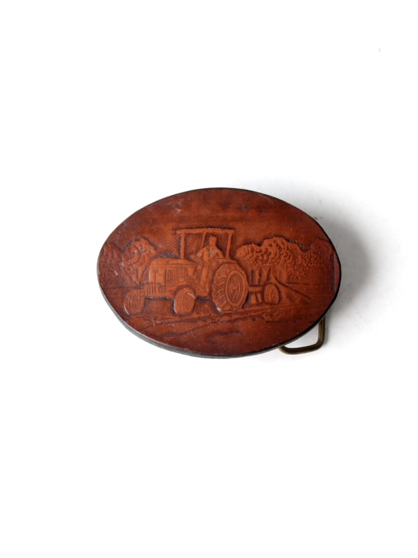 Vintage Oval Leather Belt Buckle with Farmer Design: Vintage Oval Leather Belt Buckle with Farmer Design This vintage leather belt buckle showcases a beautifully stamped depiction of a farmer plowing his field. The oval-shaped buckle is complemented by