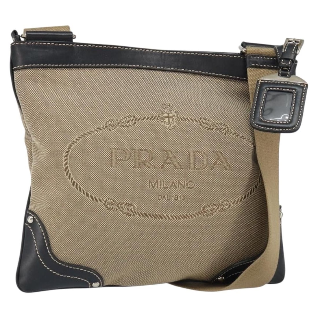 Prada Beige Canvas Shoulder Bag with Gold Tone Details and Name Tag: Prada Beige Canvas Shoulder Bag with Gold Tone Details and Name Tag This PRADA shoulder bag features a beige and gold canvas exterior, offering a chic and versatile style. Made in Italy, it includes a