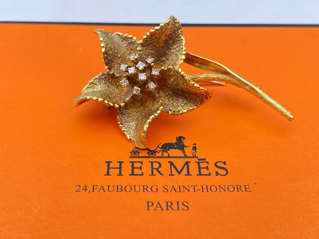 HERMES 18K Gold Diamond Flower Brooch Ruby with Box: HERMES 18K Gold Diamond Flower Brooch Ruby with Box Presenting an exquisite HERMES 18K yellow gold brooch featuring a stunning diamond flower design. This piece is fully signed, numbered, and hallmark