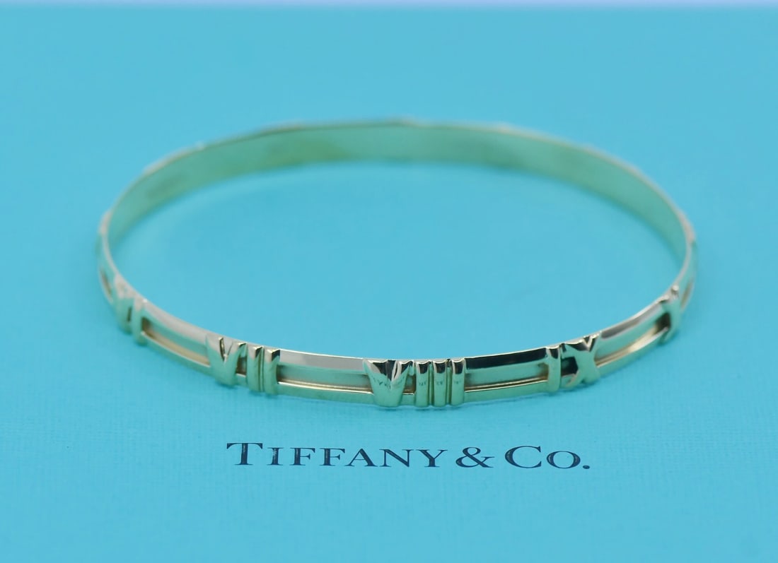 18k Yellow Gold Atlas Bangle Bracelet by Tiffany & Co: 18k Yellow Gold Atlas Bangle Bracelet by Tiffany & Co This Tiffany & Co. Atlas bangle bracelet is crafted from 18k yellow gold and features a sleek, minimalist design without stones. It is pre-owned a