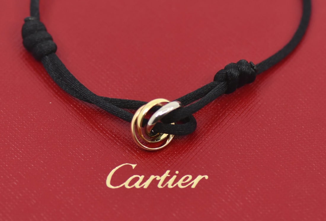 18k Multi-Tone Gold Trinity String Bracelet by Cartier with Pouch: 18k Multi-Tone Gold Trinity String Bracelet by Cartier with Pouch This is a Cartier Trinity bracelet crafted from 18k multi-tone gold and features a chain style on a string. The bracelet does not have