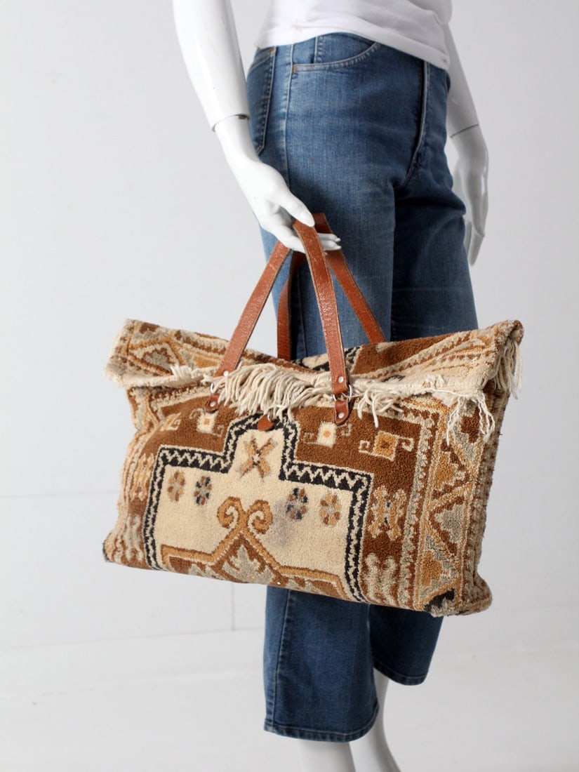 1960s Vintage Wool Carpet Bag with Leather Handles: 1960s Vintage Wool Carpet Bag with Leather Handles This vintage 1960s carpet bag is a handcrafted masterpiece, made from beautiful wool and showcasing a stunning palette of warm brown, gold, and cream