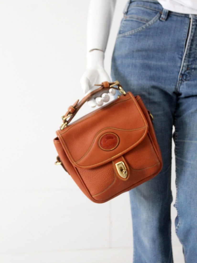 Vintage Dooney & Burke Chestnut Leather Top Handle Bag: Vintage Dooney & Burke Chestnut Leather Top Handle Bag This vintage Dooney & Burke top handle bag is crafted from rich chestnut brown leather. It features a secure flap closure with a brass twisting l