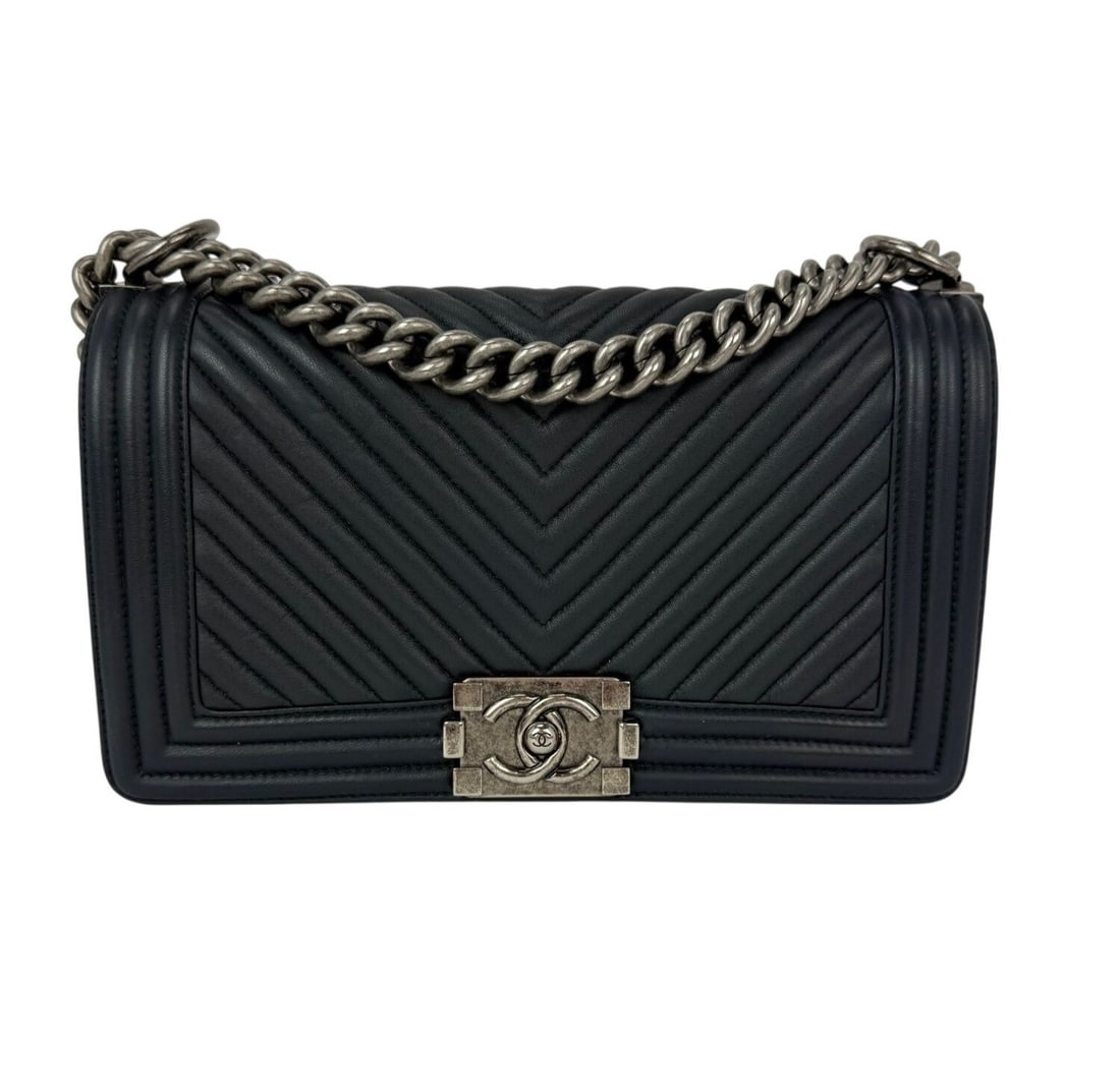 Medium Navy Blue Boy Chevron Quilted Shoulder Bag by CHANEL: Medium Navy Blue Boy Chevron Quilted Shoulder Bag by CHANEL This CHANEL Boy shoulder bag features chevron quilting in navy blue lambskin leather with a medium-sized rectangular silhouette. The bag is