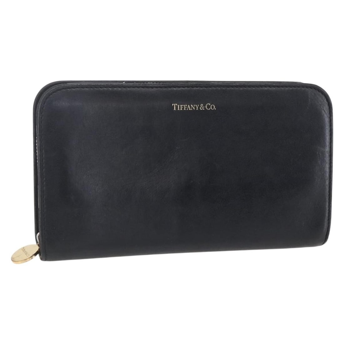 Leather Zip Around Wallet by Tiffany Black 21cm by 12cm: Leather Zip Around Wallet by Tiffany Black 21cm by 12cm This pre-owned Tiffany & Co. zip-around wallet for women is crafted from black leather. It features a zip-around closure and shows signs of wear