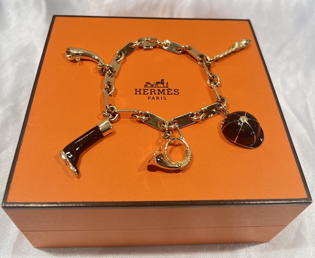 Hermes 18K Gold Enamel Charm Bracelet with 5 Hunting Charms and Box: Hermes 18K Gold Enamel Charm Bracelet with 5 Hunting Charms and Box This exquisite French Hermes charm bracelet is crafted from 18K yellow gold and features stunning enamel detailing. It showcases a h