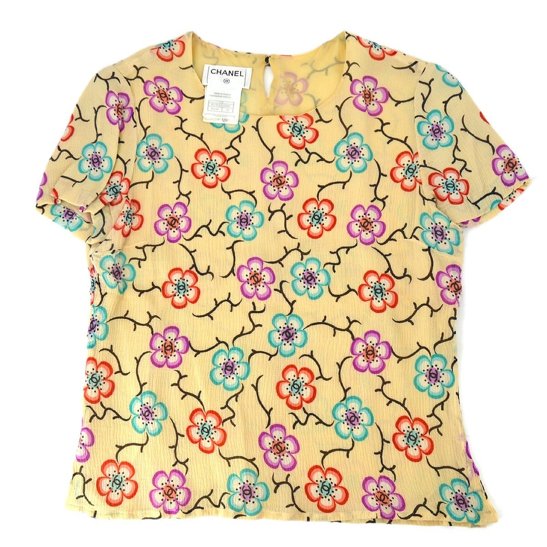 Chanel 01S Silk Flower Pattern Short Sleeve Blouse Beige: Chanel 01S Silk Flower Pattern Short Sleeve Blouse Beige Elevate your casual wardrobe with this exquisite Chanel short sleeve blouse, featuring a charming flower pattern that captures the essence of s