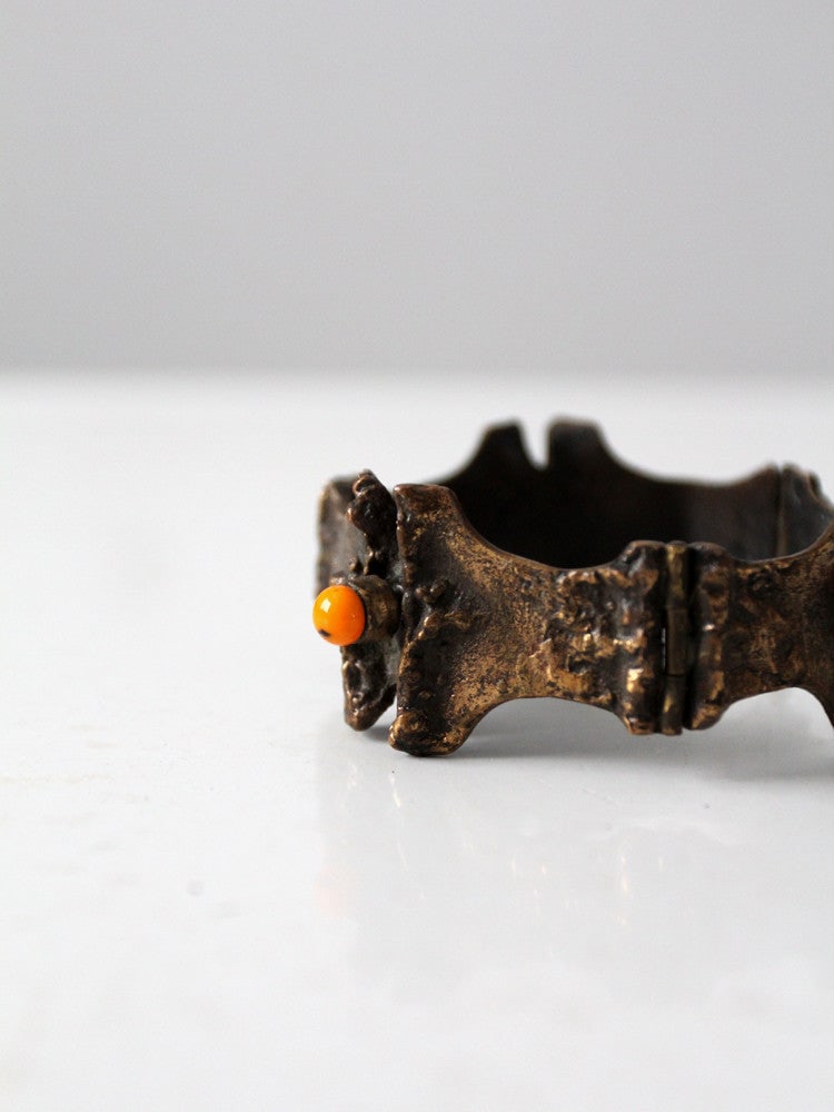 1970s Vintage Bronze Hinged Cuff Bracelet with Orange Beads: 1970s Vintage Bronze Hinged Cuff Bracelet with Orange Beads Discover a unique piece from the 1970s with this vintage bronze hinged cuff bracelet. Hand-crafted, this heavy metal bracelet features three