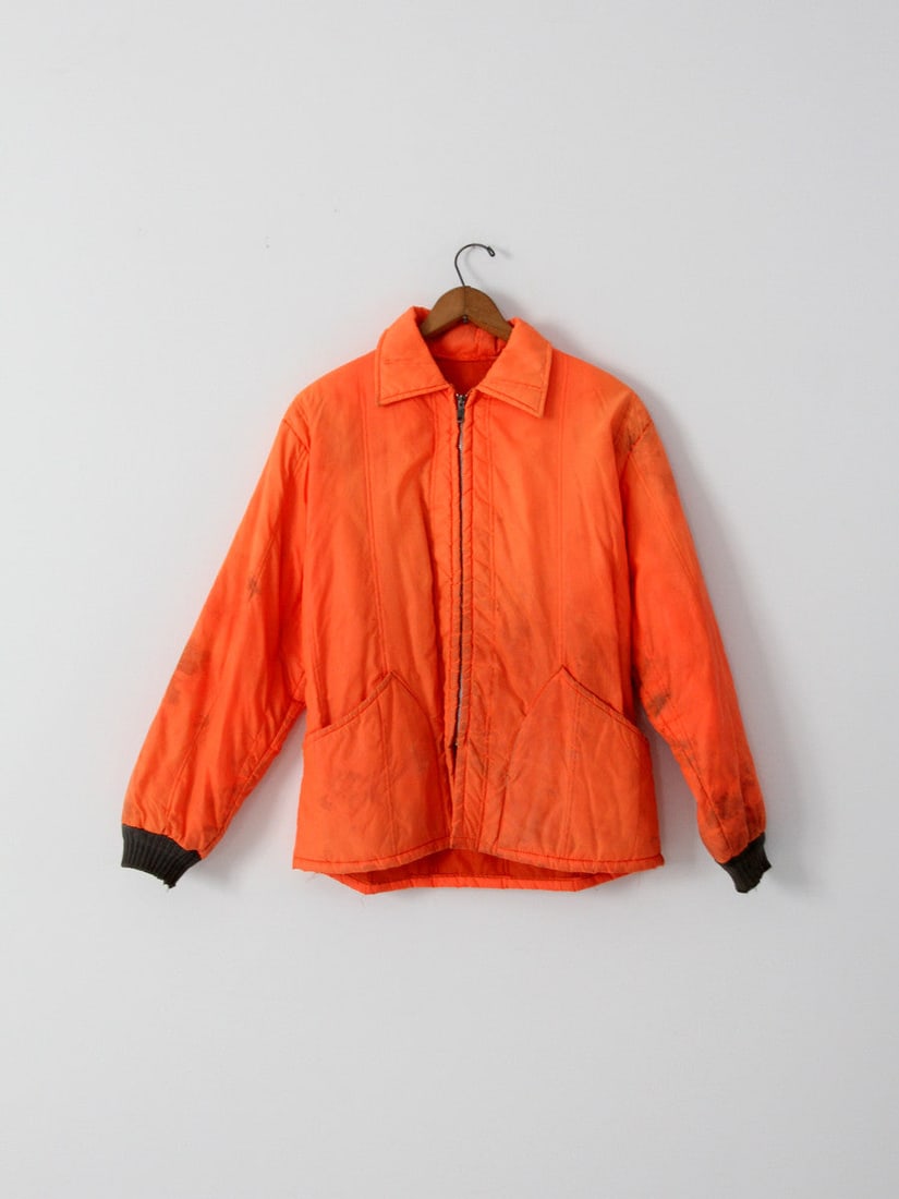 1970s Neon Orange Nylon Hunting Jacket with Olive Green Cuffs: 1970s Neon Orange Nylon Hunting Jacket with Olive Green Cuffs This vintage 1970s nylon hunting jacket is a striking neon orange piece designed for outdoor enthusiasts. It features rib knit cuffs in ol
