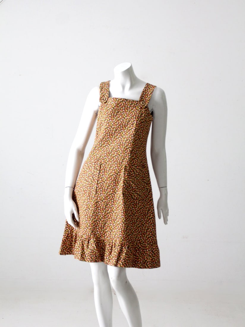 1970s Vintage Floral Brown Dress with Ruffle Hemline: 1970s Vintage Floral Brown Dress with Ruffle Hemline Embrace the essence of the 1970s with this vintage floral dress. The dress showcases a beautiful brown fabric adorned with a vibrant floral pattern