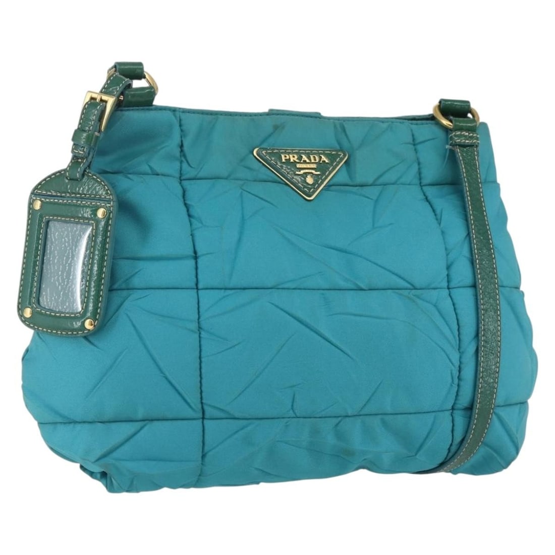 Prada Turquoise Blue Nylon Shoulder Bag with Gold Accents and Name Tag: Prada Turquoise Blue Nylon Shoulder Bag with Gold Accents and Name Tag This PRADA shoulder bag is crafted from turquoise blue nylon with gold-tone accents. Made in Italy, it features a structured desi