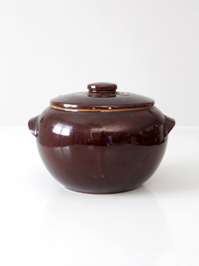 Vintage USA Pottery Covered Bowl with Chocolate-Brown Glaze: Vintage USA Pottery Covered Bowl with Chocolate-Brown Glaze This vintage USA pottery covered bowl showcases a rich chocolate-brown glaze and a rounded form, complemented by a fitted lid with side hand