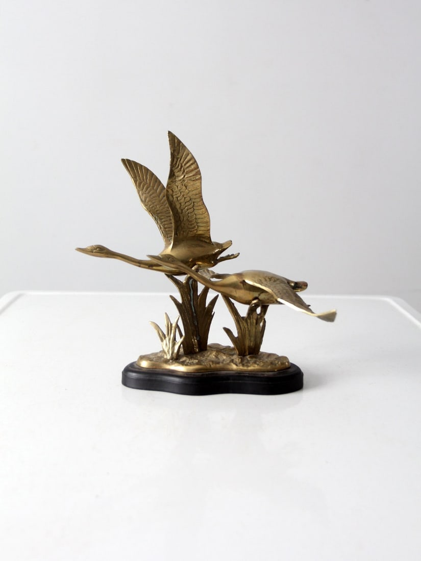 Vintage Brass Birds Sculpture on Black Wooden Base: Vintage Brass Birds Sculpture on Black Wooden Base This vintage brass birds sculpture captures the beauty of two birds soaring across marshlands. Crafted from high-quality brass, the sculpture is moun
