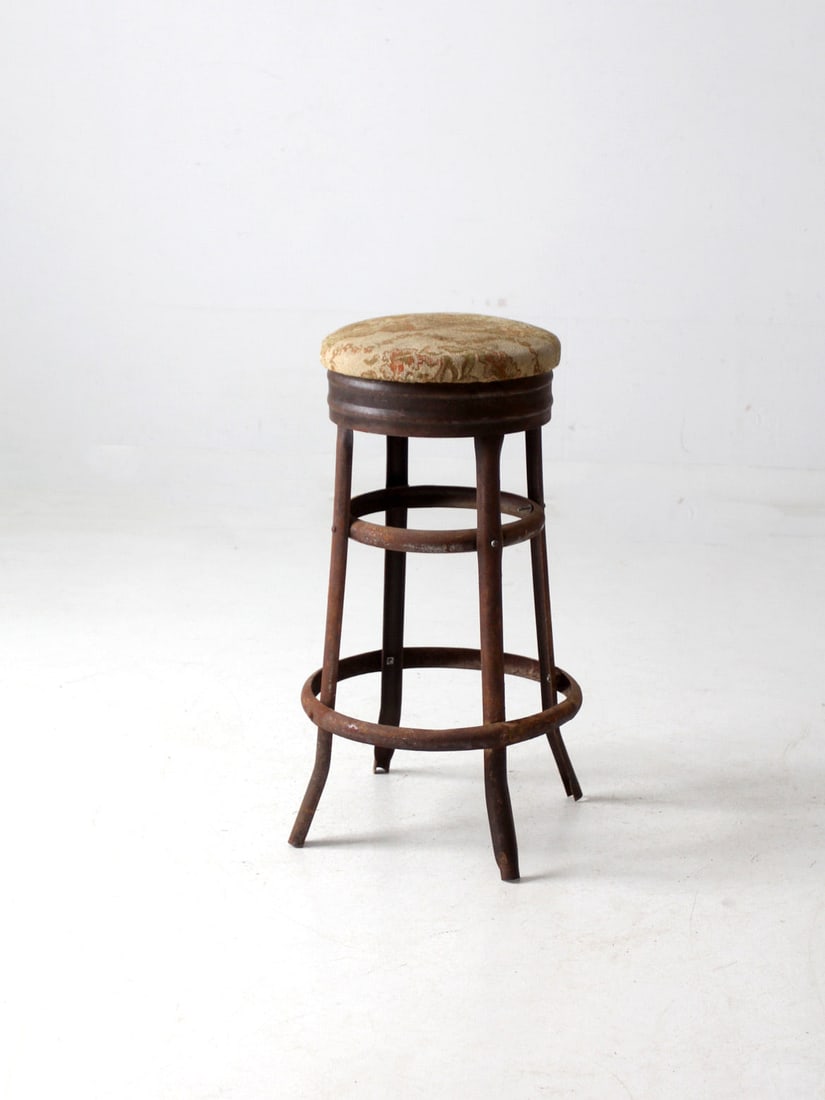 Vintage Industrial Metal Stool with Tapestry Seat: Vintage Industrial Metal Stool with Tapestry Seat This antique metal stool combines industrial and rustic design elements, featuring a weathered finish that adds character and charm. The upholstered s