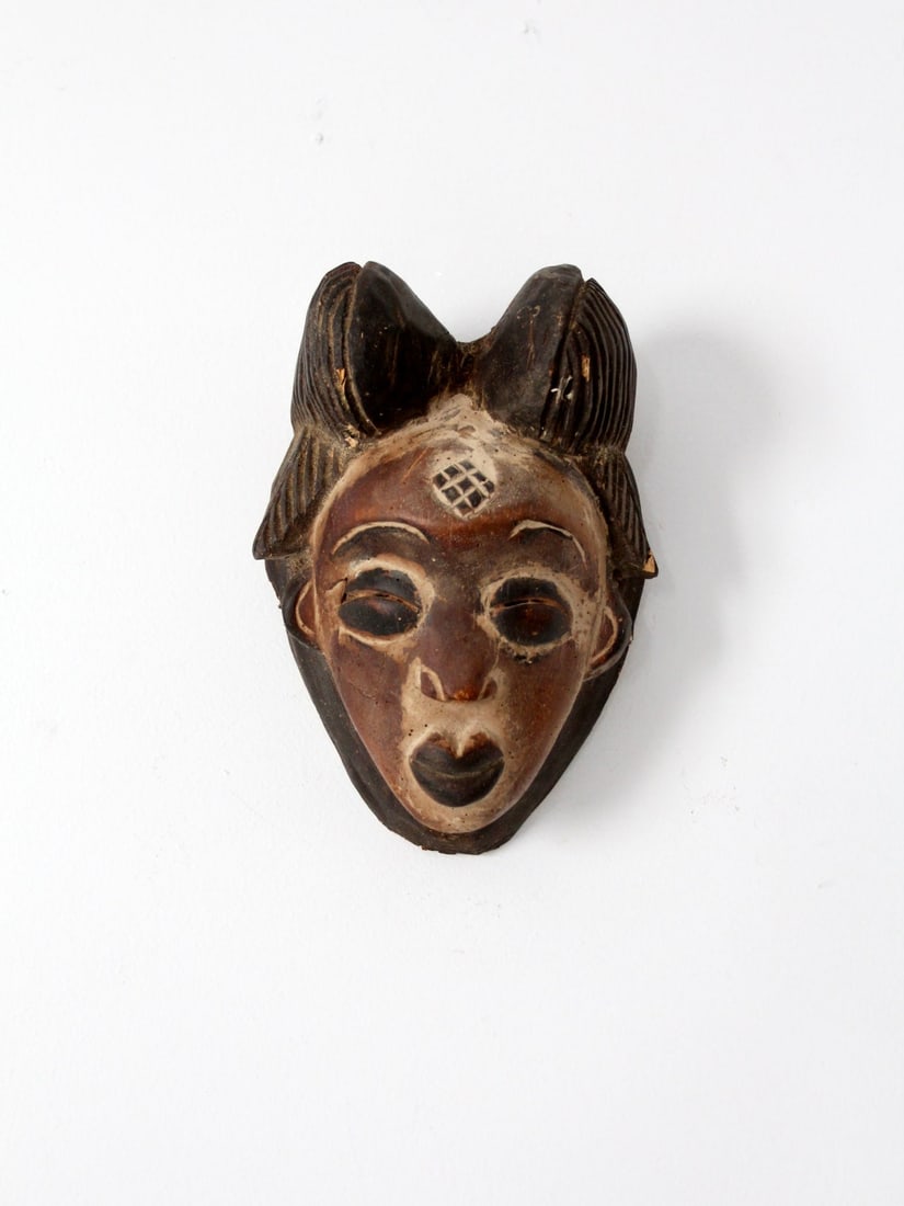 Vintage Punu Tribal Mask Hand-Carved Wooden Wall Art: Vintage Punu Tribal Mask Hand-Carved Wooden Wall Art This vintage African tribal mask, crafted by the Punu people, is a stunning hand-carved wooden piece featuring intricate brown tone details. Design
