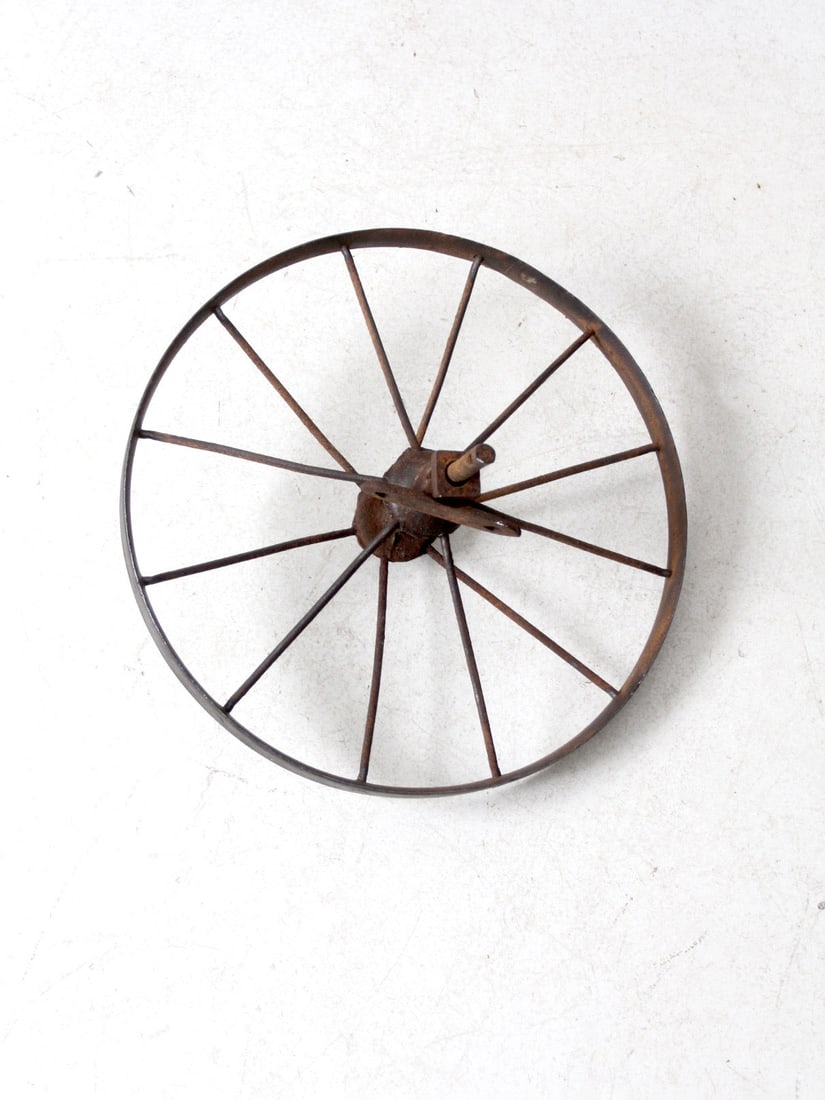 Vintage Antique Iron Cart Wheel Decorative Garden Piece: Vintage Antique Iron Cart Wheel Decorative Garden Piece This antique iron cart wheel showcases a narrow profile and mounted hubs, highlighting its industrial heritage. Formerly part of a wheelbarrow o