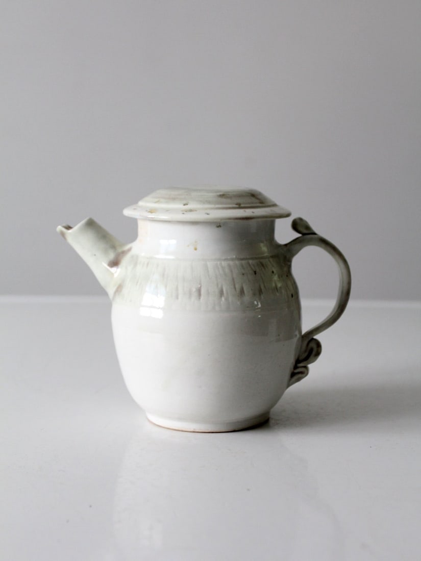 Handcrafted Vintage Ceramic Teapot with Olive Gray Accents Signed Artist: Handcrafted Vintage Ceramic Teapot with Olive Gray Accents Signed Artist This vintage handcrafted ceramic teapot is a unique piece of studio pottery, featuring a stunning white glaze adorned with subt
