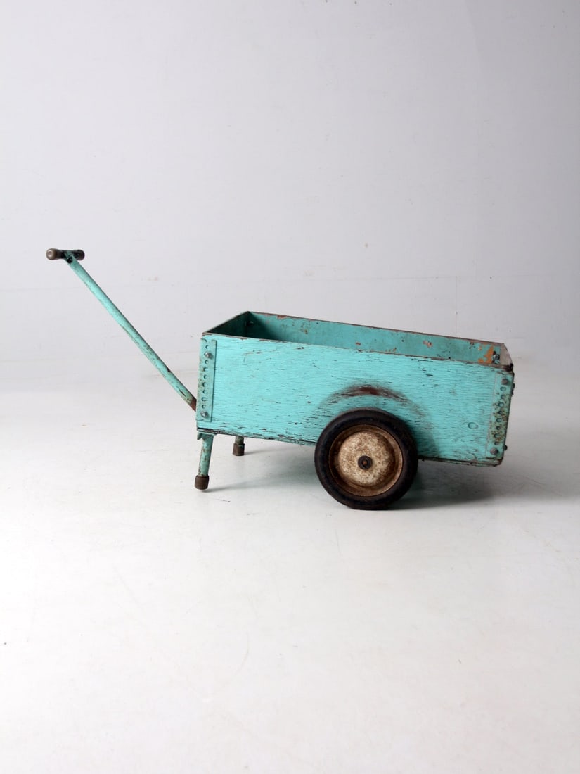 Rustic Vintage Wooden Garden Cart with Worn Teal Finish: Rustic Vintage Wooden Garden Cart with Worn Teal Finish This vintage wooden garden cart showcases a charming worn teal finish, complete with two side wheels and a sturdy metal handle for effortless ma