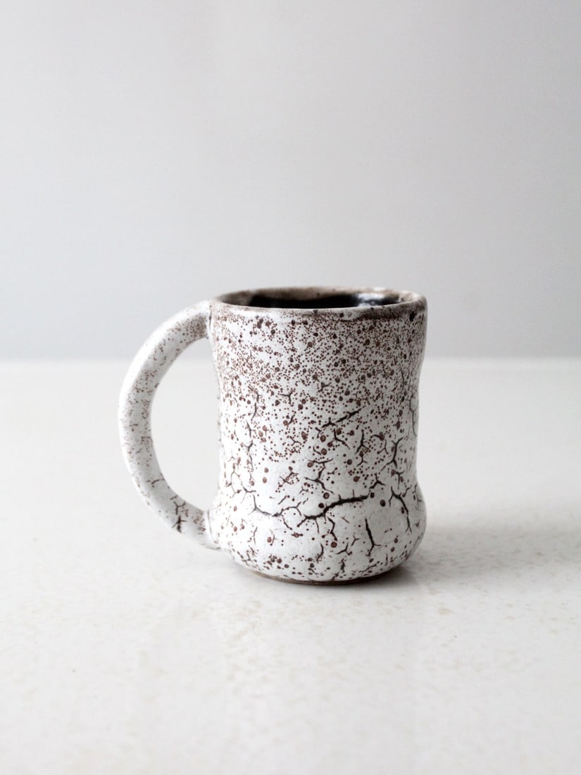Handmade Vintage Ceramic Mug with Speckled White Crackle Glaze: Handmade Vintage Ceramic Mug with Speckled White Crackle Glaze This vintage studio pottery mug is handmade and features a softly contoured form with a speckled white glaze and fine crackle detailing.