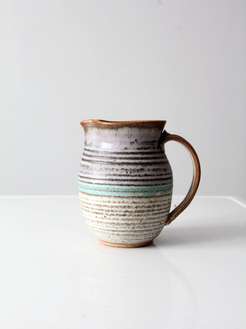 Signed Vintage Studio Pottery Pitcher Lavender Turquoise Glaze: Signed Vintage Studio Pottery Pitcher Lavender Turquoise Glaze This vintage studio pottery pitcher is a stunning example of hand-crafted artistry. Featuring a unique speckled pottery design, it is ado