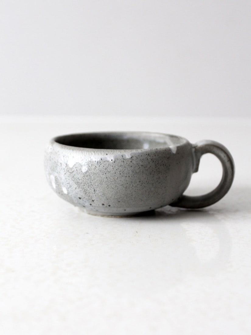 Handmade Vintage Studio Pottery Mug with Artist Signature: Handmade Vintage Studio Pottery Mug with Artist Signature This vintage handmade studio pottery mug showcases a unique low, wide profile that sets it apart. Its pale gray speckled glaze is beautifully