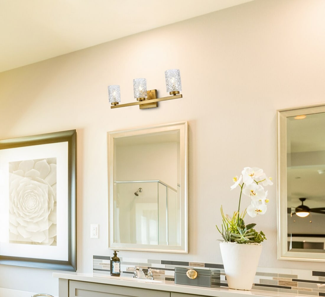 Cassie 3-Light Brass and Glass Wall Sconce for Modern Interiors: Cassie 3-Light Brass and Glass Wall Sconce for Modern Interiors This modern wall sconce features a brass finish steel frame with three downward-facing lights, each covered by a clear glass cylindrical