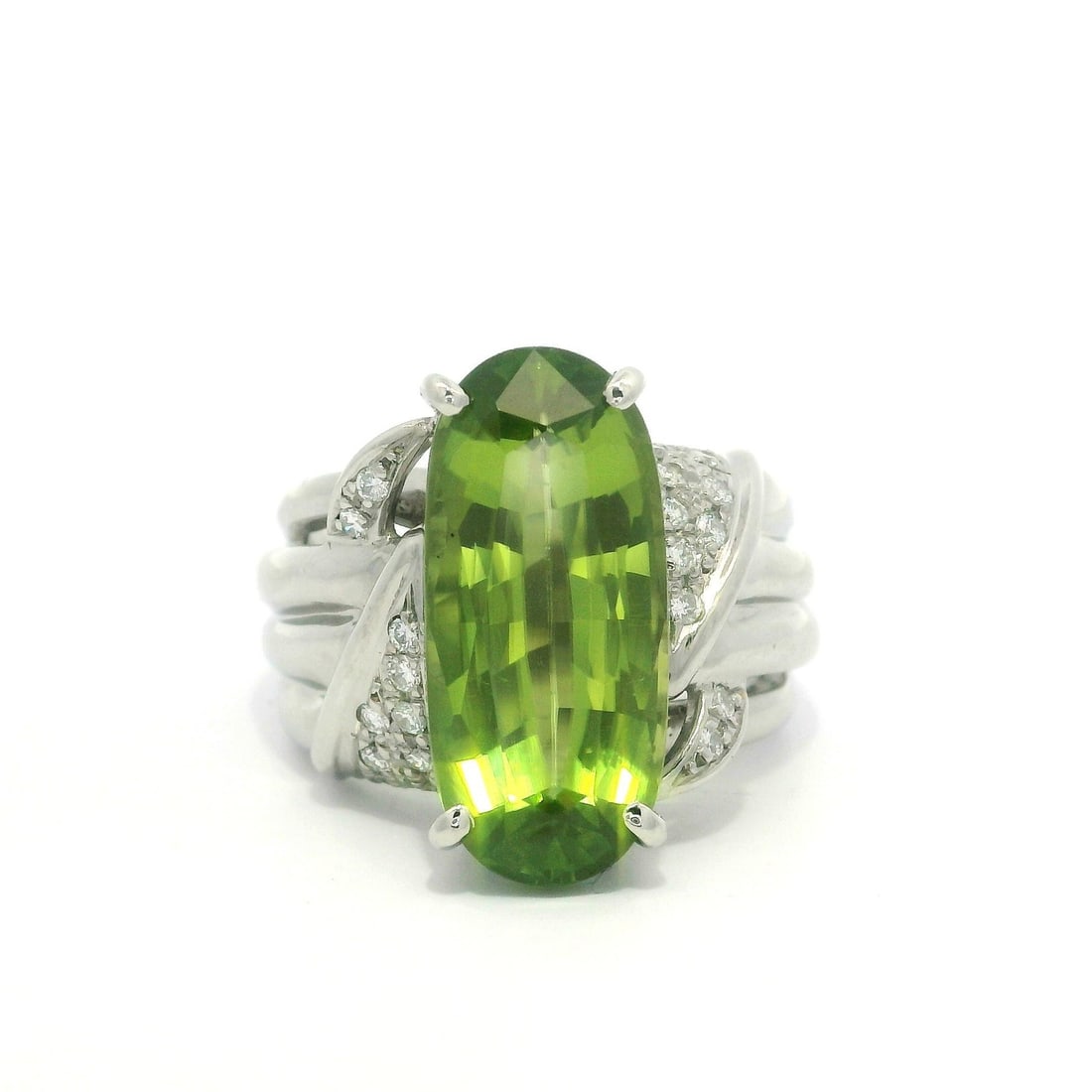 Platinum 7.61ctw Elongated Oval Peridot Diamond Cocktail Ring: Platinum 7.61ctw Elongated Oval Peridot Diamond Cocktail Ring This exquisite cocktail ring features a stunning large elongated oval peridot, expertly prong set to showcase its vibrant green hue. The n