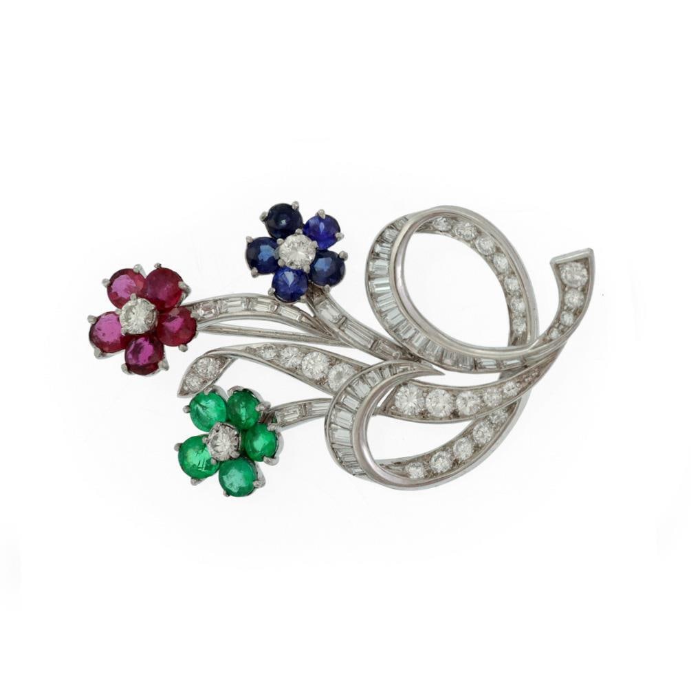 Platinum Floral Brooch with Diamond Ruby Emerald Sapphire Accents: Platinum Floral Brooch with Diamond Ruby Emerald Sapphire Accents This exquisite brooch showcases a beautiful floral bouquet design, crafted from high-quality platinum with a polished finish. It featu