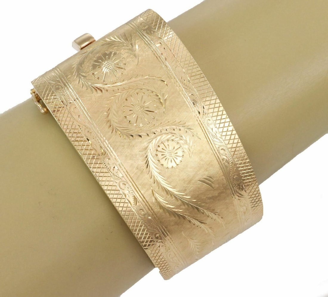 14k Yellow Gold Wide Hinged Bangle Bracelet Polished Finish: 14k Yellow Gold Wide Hinged Bangle Bracelet Polished Finish This wide fancy hinged bangle bracelet is crafted in solid 14k yellow gold, showcasing a bold polished design with a sculptural wide profile