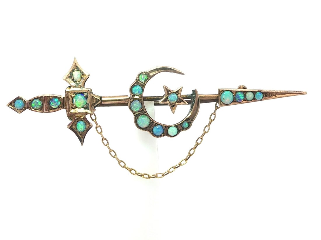 Victorian Era Yellow Gold Jabot Pin with Opal Crescent and Star Motif: Victorian Era Yellow Gold Jabot Pin with Opal Crescent and Star Motif This antique Victorian brooch features a sword and crescent star design adorned with 18 natural round cabochon-cut opals. The opal