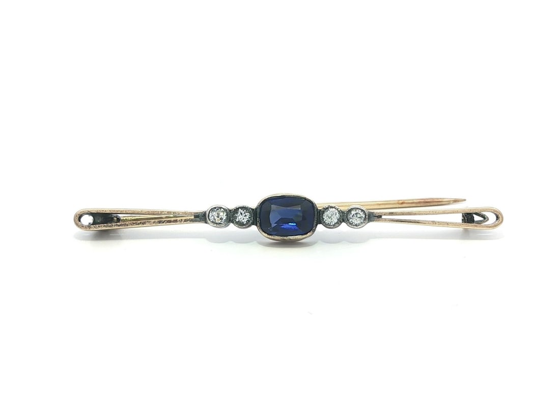 Antique Bar Brooch in 14k Yellow Gold and Silver with Blue and White Stones: Antique Bar Brooch in 14k Yellow Gold and Silver with Blue and White Stones This antique bar pin brooch features a cushion-cut blue stone, bezel set and accented by four round-cut white stones. Crafte