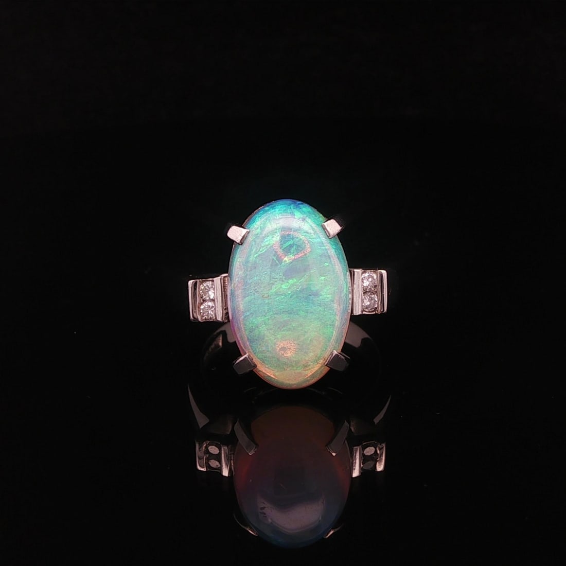 Platinum Cocktail Ring with Oval Opal and Diamond Accents: Platinum Cocktail Ring with Oval Opal and Diamond Accents This platinum cocktail ring features a long, elongated oval opal with a vibrant play of green, violet, and orange colors. The natural opal is