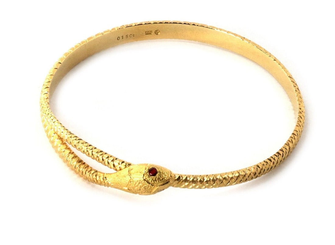 18k Yellow Gold Snake Bypass Bangle with Ruby Accents: 18k Yellow Gold Snake Bypass Bangle with Ruby Accents This vintage bangle bracelet is crafted from 18k yellow gold and features a textured snake bypass design. The bracelet is accented with rubies tot