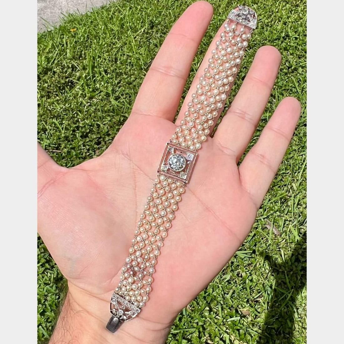 Art Deco Platinum Bracelet with Natural Pearls and Diamonds: Art Deco Platinum Bracelet with Natural Pearls and Diamonds This exquisite Art Deco bracelet showcases a stunning combination of natural pearls and diamonds. The centerpiece features an approximate 2.