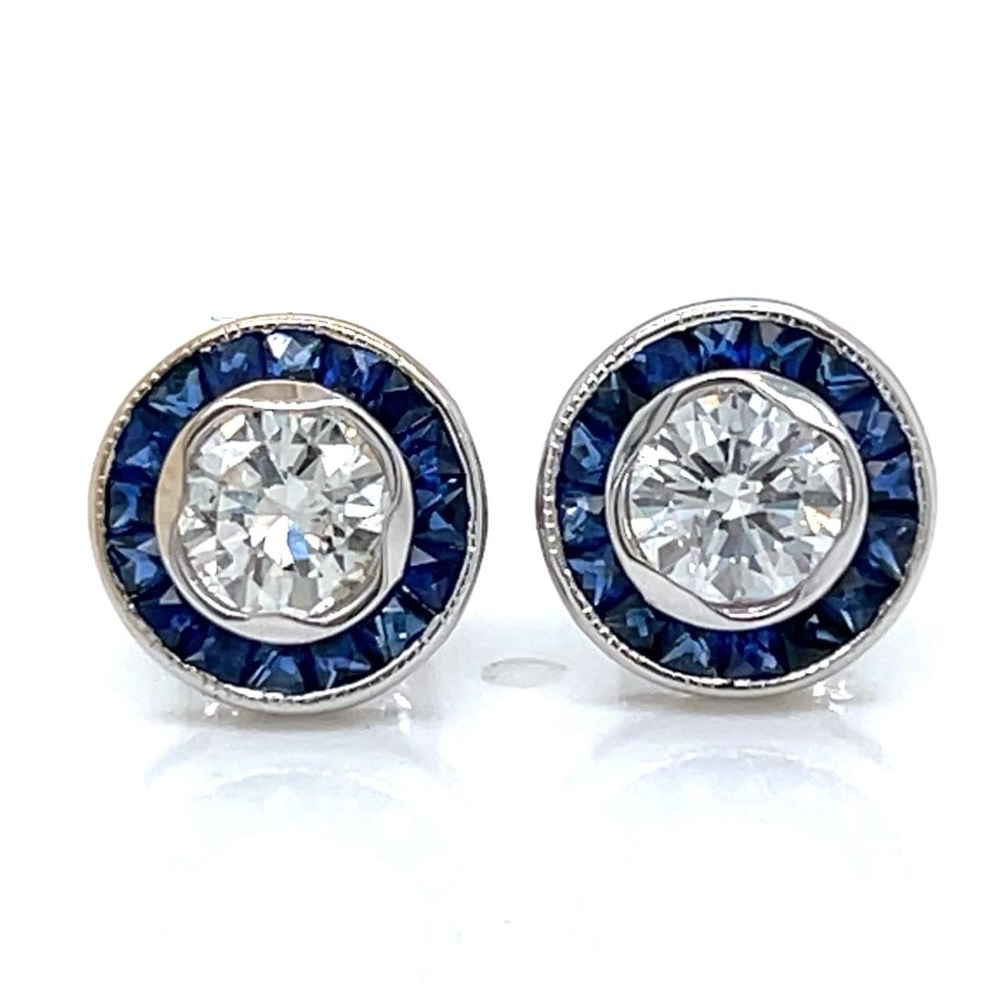 Diamond and Sapphire Stud Earrings in 18K White Gold: Diamond and Sapphire Stud Earrings in 18K White Gold These stud earrings are crafted in 18K white gold and feature two diamonds totaling 1.03 carats with E-F color and VS1-SI1 clarity. The earrings ar