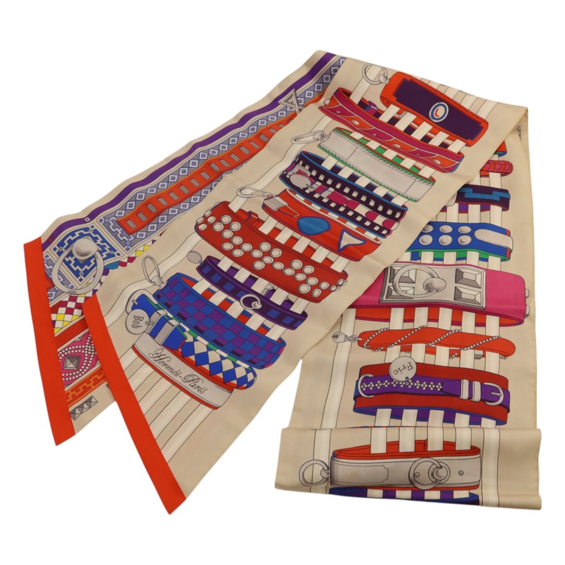 Silk Maxi Twilly Scarf by Hermes in Beige and Red: Silk Maxi Twilly Scarf by Hermes in Beige and Red Hermes Maxi Twilly scarf crafted from silk features a beige base with red and multicolor accents. Designed for women, this regular size scarf adds a v