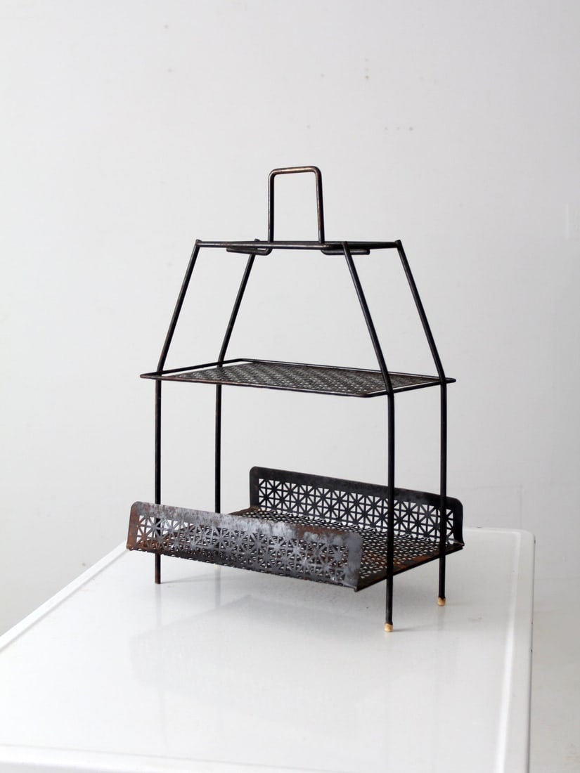 Mid-Century Black Metal Stand with Patterned Cut-Out Design: Mid-Century Black Metal Stand with Patterned Cut-Out Design This mid-century tiered metal stand, dating from the mid 20th century, showcases a stylish black finish with a unique patterned cut-out desi