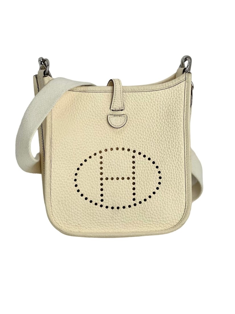 Hermes Evelyne TPM Nata White Crossbody Bag with Silver Hardware: Hermes Evelyne TPM Nata White Crossbody Bag with Silver Hardware Introducing the elegant Hermes Taurillon Clemence Evelyne TPM Crossbody Bag in a pristine Nata White color. This stylish rectangular ba