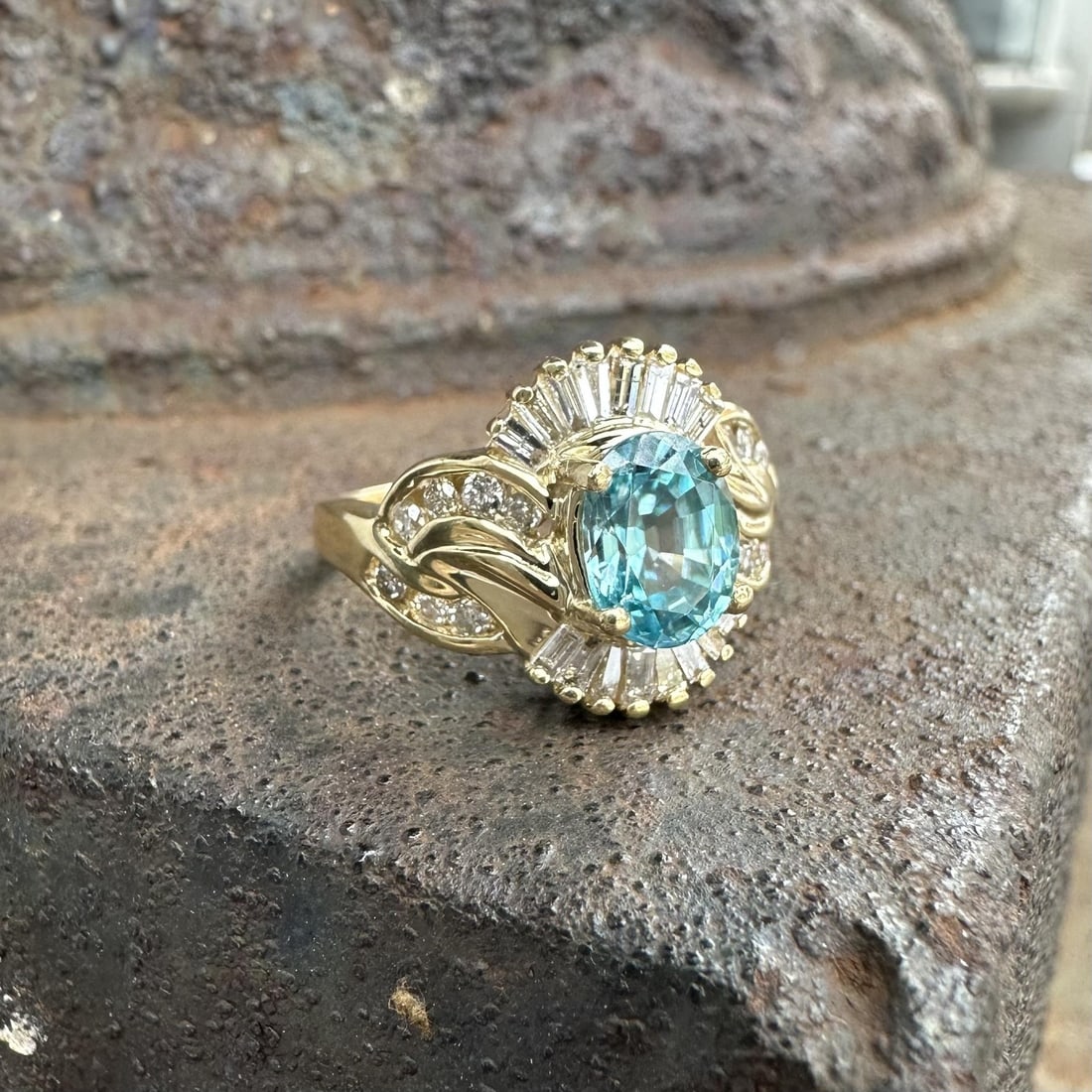Blue Topaz and Diamond Floral Band in 14k Yellow Gold Oval Design: Blue Topaz and Diamond Floral Band in 14k Yellow Gold Oval Design This women's band ring features an oval brilliant-cut natural blue topaz as the centerpiece, prong-set and measuring approximately 8x6