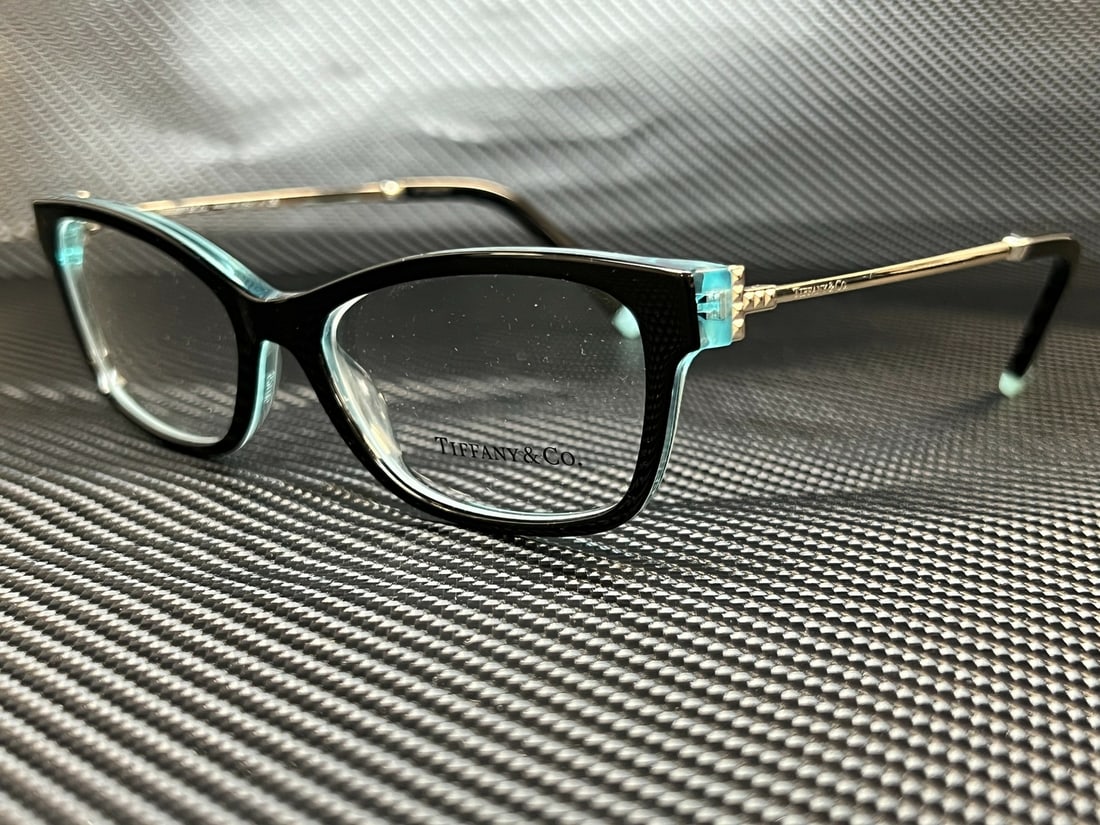 Tiffany & Co. TF2204 8285 Black On Crystal Rectangle Eyeglasses: Tiffany & Co. TF2204 8285 Black On Crystal Rectangle Eyeglasses Experience elegance with Tiffany & Co.'s TF2204 8285 eyeglasses, featuring a sophisticated black on crystal frame. These stylish rectang