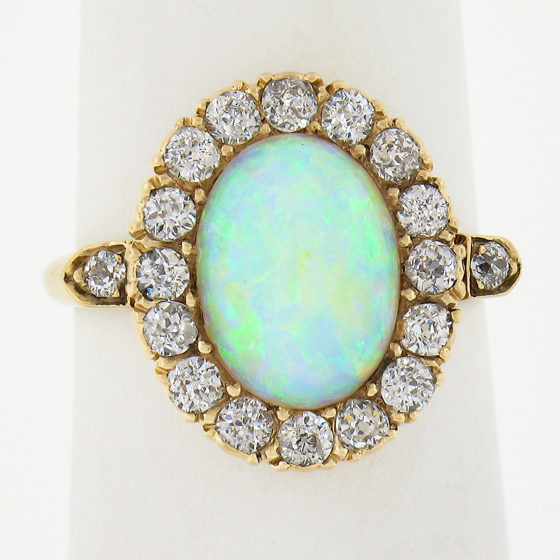 Victorian 14K Gold Oval Opal Diamond Halo Ring 0.80ctw: Victorian 14K Gold Oval Opal Diamond Halo Ring 0.80ctw This exquisite Antique Victorian ring showcases a captivating oval opal solitaire, expertly crafted in solid 14K yellow gold. The opal, measuring