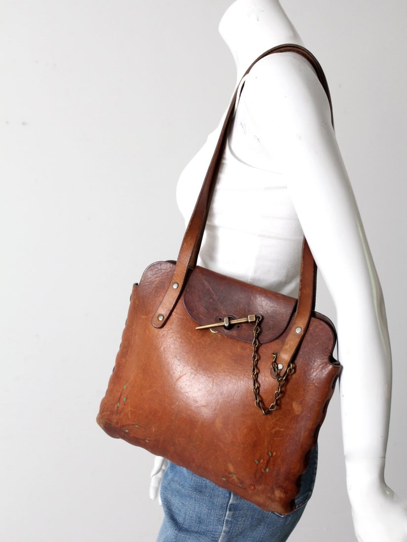 1960s Vintage Hippie Handcrafted Leather Shoulder Bag: 1960s Vintage Hippie Handcrafted Leather Shoulder Bag Embrace the spirit of the 1960s with this vintage hippie shoulder bag, expertly hand-crafted from rich brown leather. The bag showcases thick leat