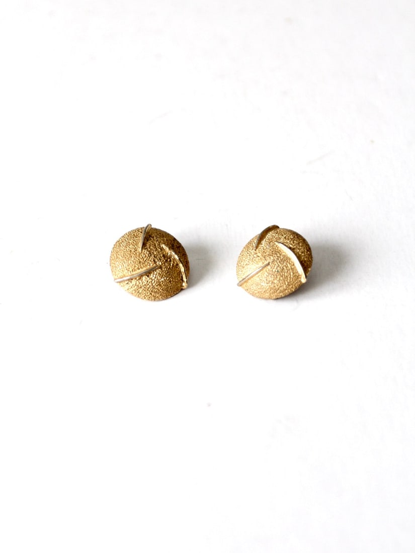 1960s Vintage Clip-On Earrings Gold Tone Mod Design: 1960s Vintage Clip-On Earrings Gold Tone Mod Design Step back in time with these stunning vintage 1960s clip-on earrings. Featuring a textured gold tone finish, these round earrings showcase a dynamic