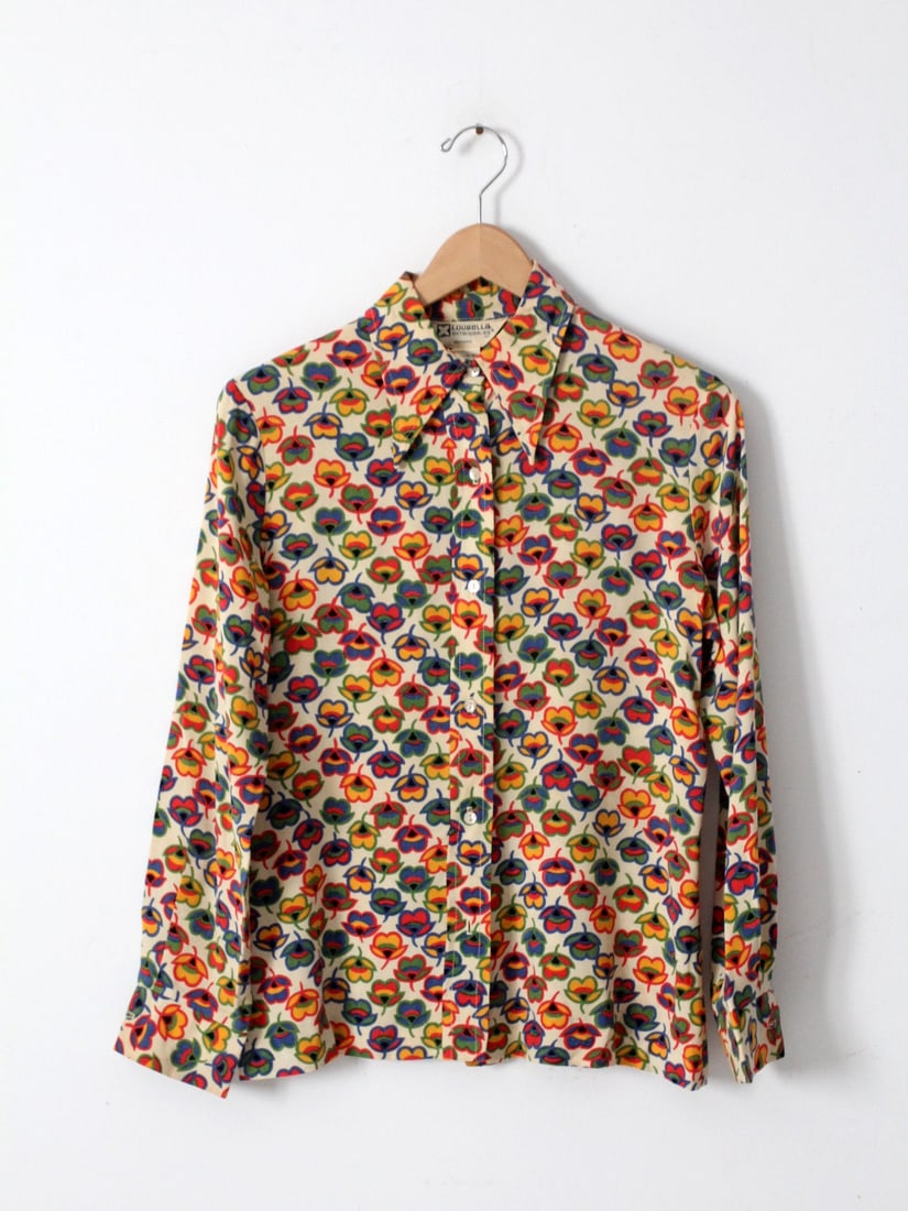 Loubella Extendables 1970s Nylon Blouse With Rainbow Floral Pattern: Loubella Extendables 1970s Nylon Blouse With Rainbow Floral Pattern This vintage 1970s Loubella Extendables button down blouse is crafted from silky cream nylon and showcases a vibrant flower power pr