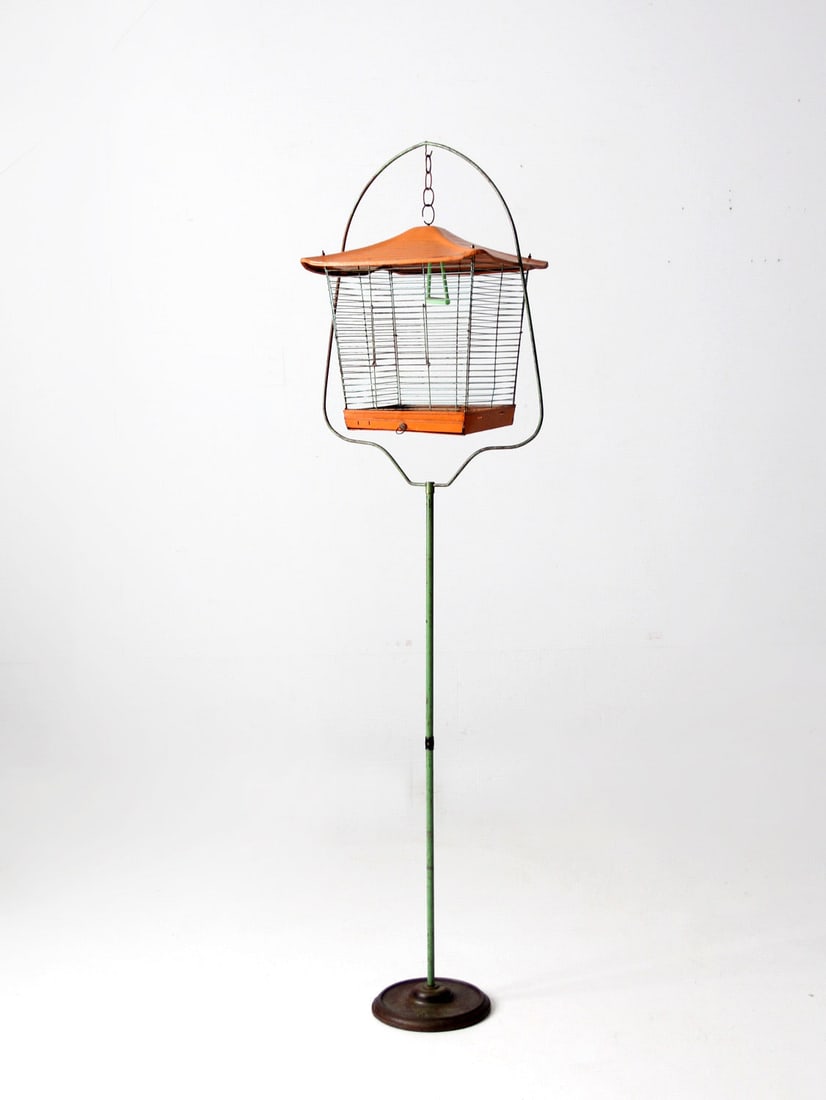 Mid-Century Bird Cage with Stand Orange Roof Celadon Green Iron Base: Mid-Century Bird Cage with Stand Orange Roof Celadon Green Iron Base This charming mid-century bird cage with stand features a distinctive orange peaked roof and slender bars. The cage includes an ora