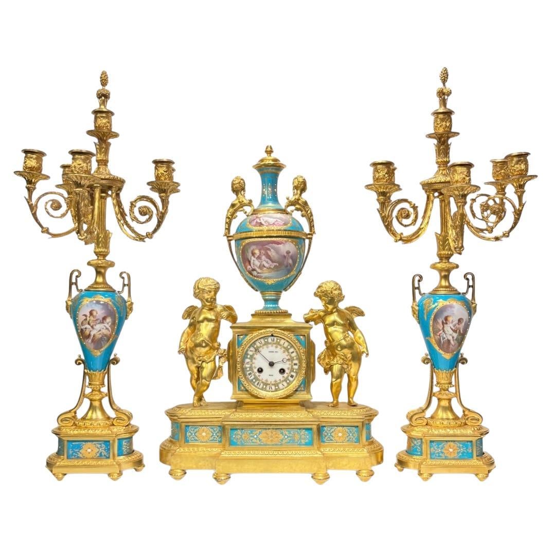 French Louis XVI Style Sevres Porcelain Bronze Clock and Candelabra Set of 3: French Louis XVI Style Sevres Porcelain Bronze Clock and Candelabra Set of 3 This late 19th-century French garniture set features a mantel clock and a pair of candelabra crafted by Raingo Freres of Pa